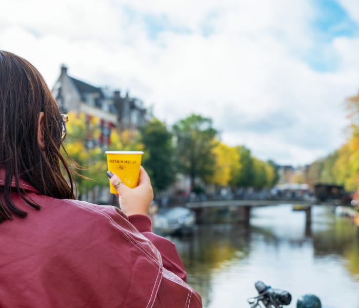 Girl on bridge with coffee in Amsterdam