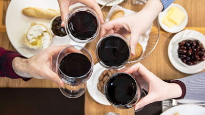 Winiarnia Brasserie – ujęcie czterech osób trzymających kieliszki z czerwonym winem od góry