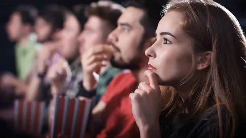 Kino — rząd ludzi oglądających film i jedzących popcorn