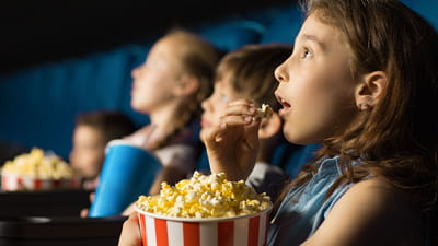 Films pour enfants - rangée d'enfants regardant un film avec leur pop-corn