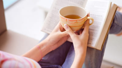 Ruhebereich – Frau liest ein Buch mit einer Tasse Tee