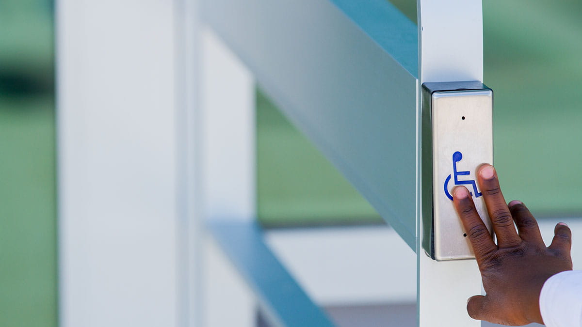 Man with disability pushing disabled access button