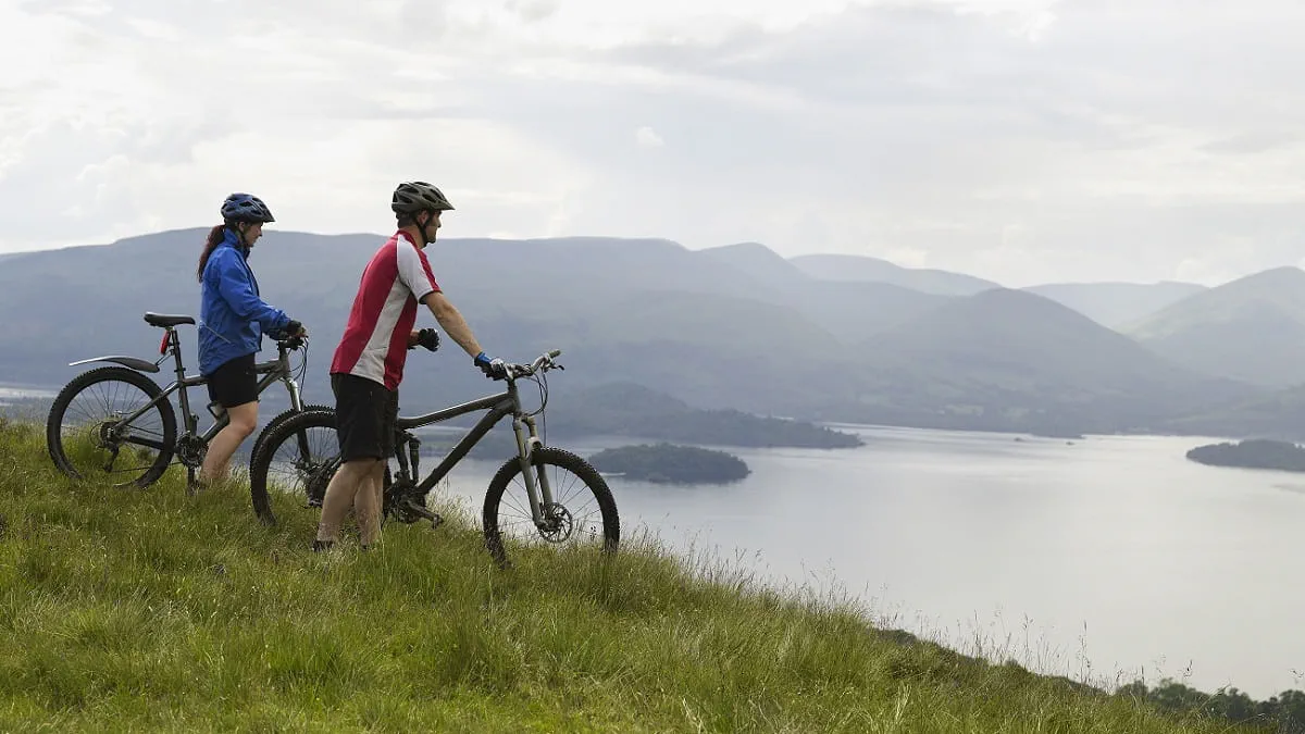 twee fietsers kijken uit over het landschap van Schotland vanaf een berg